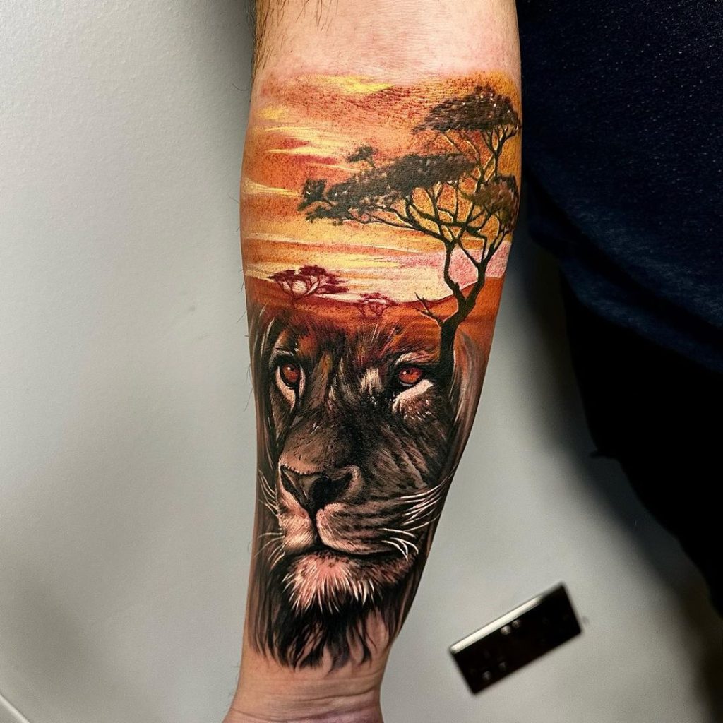 腕にライオンと風景画のタトゥー
