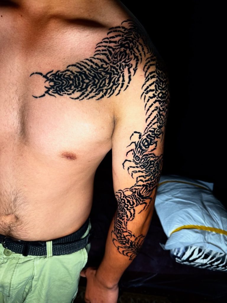 胸から腕にかけて這う百足(ムカデ)のトライバルタトゥー