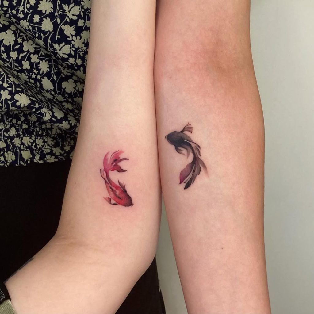 A matching pair tattoo of sumi-ink style goldfish on the arm