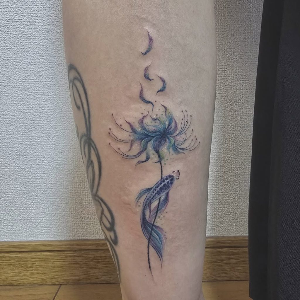 A dreamy one-point goldfish tattoo with blue red spider lilies